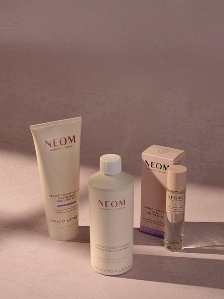 NEOM bath & body skincare products on a gradient background