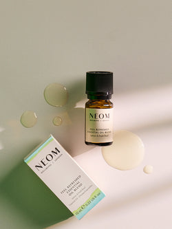 NEOM Feel Refreshed essential oil blend with lemon and basil in glass bottle with packaging on soft pastel background.