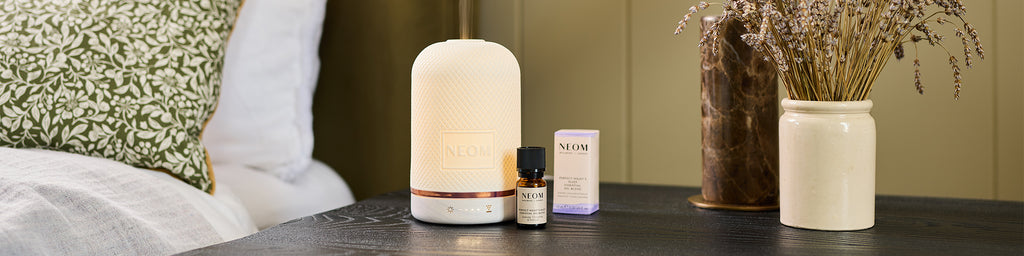 NEOM Wellbeing Pod essential oil diffuser on bedside table with Perfect Night’s Sleep essential oil blend.