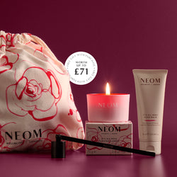 NEOM free gifts worth up to £71 featuring a lit scented candle, wick trimmer, hand balm and branded drawstring bag on a dark purple background.