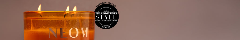 Candle with 'NEOM' text and a logo in the background