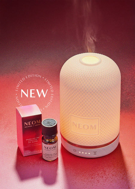 NEOM electric diffuser with essential oils on a red background