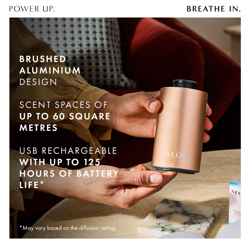 Person holding a cylindrical metallic diffuser with text about its features.