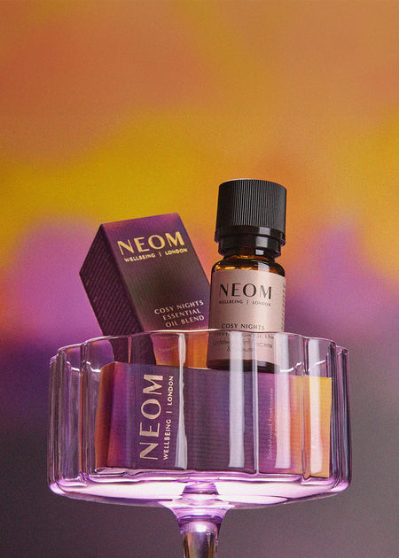 NEOM essential oil bottle and packaging on a gradient background