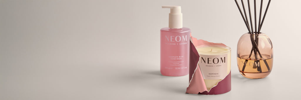 NEOM products including a hand wash, candle, and reed diffuser on a light background