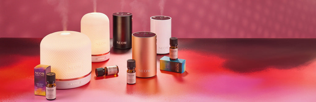 NEOM pod diffusers and essential oils on a pink background