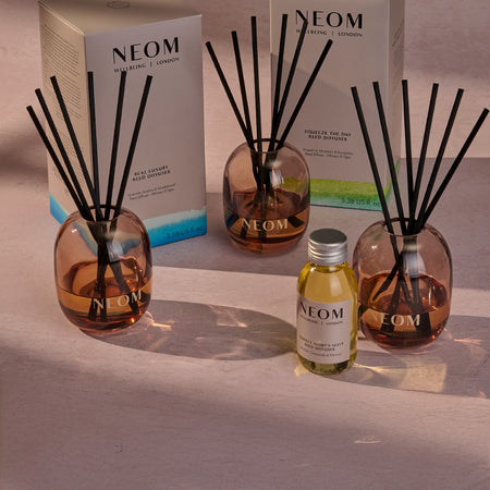 NEOM Reed diffusers and bottle on a neutral background