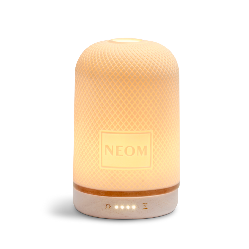 NEOM Wellbeing Pod white ceramic essential oil diffuser glowing with warm ambient light