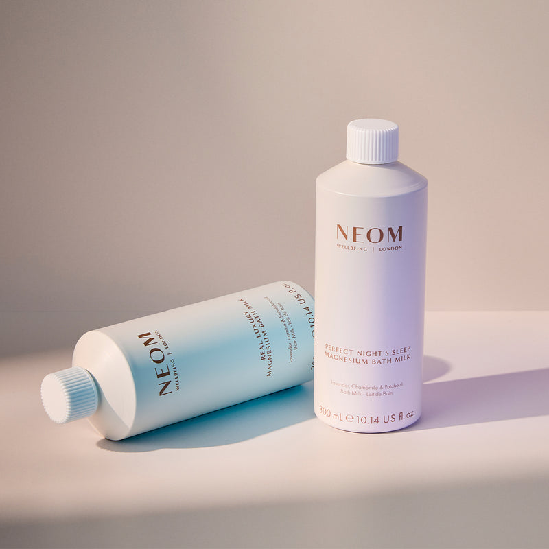 Two NEOM bath milks on a neutral background