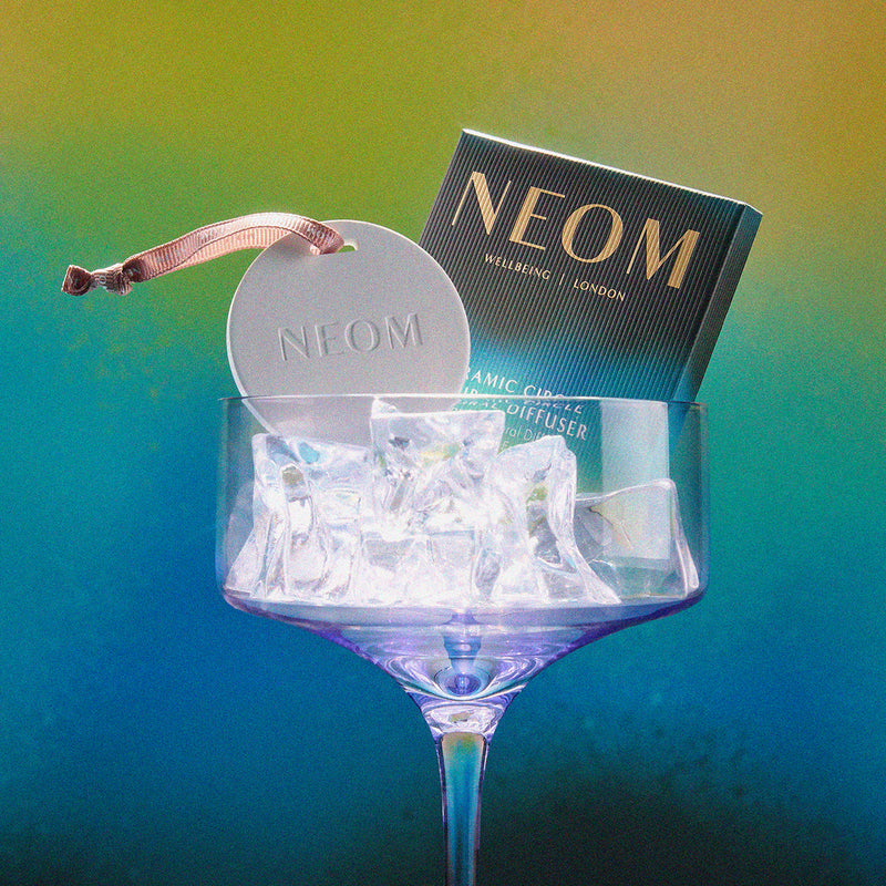 Neom diffuser in a glass with a gradient background
