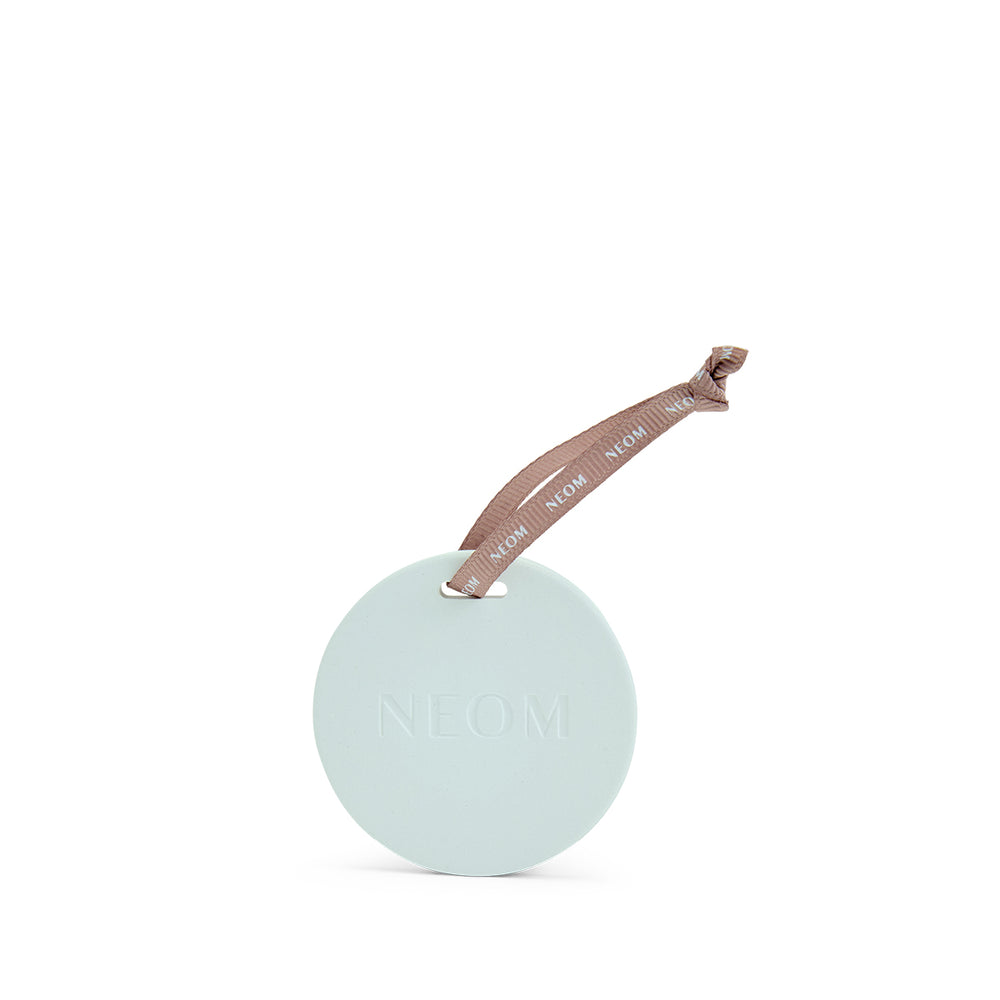 NEOM Round ceramic circle with a pink ribbon on a white background