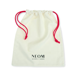 White drawstring bag with red strings and 'NEOM' branding on a white background