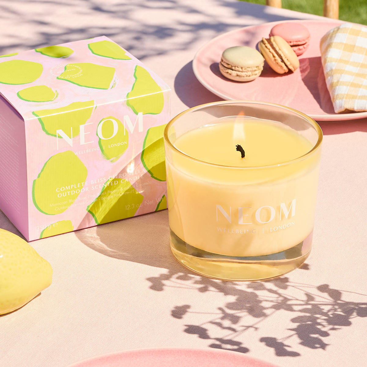 Neom candle with packaging and macarons on a table
