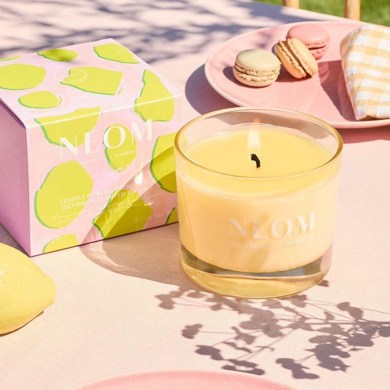 Neom candle with packaging and macarons on a table