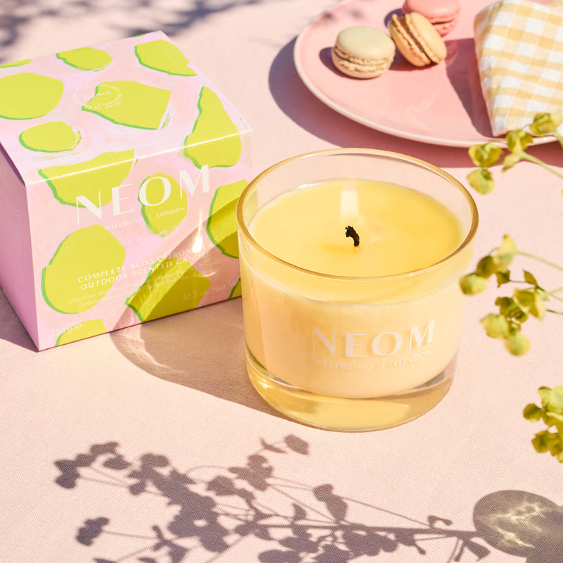 Neom candle with a pink box featuring green lime illustrations on a light pink surface.