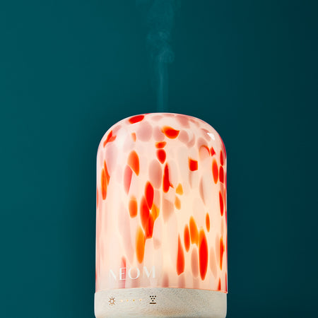 NEOM electric pod diffuser with a colourful orange, red and pink design on a teal background