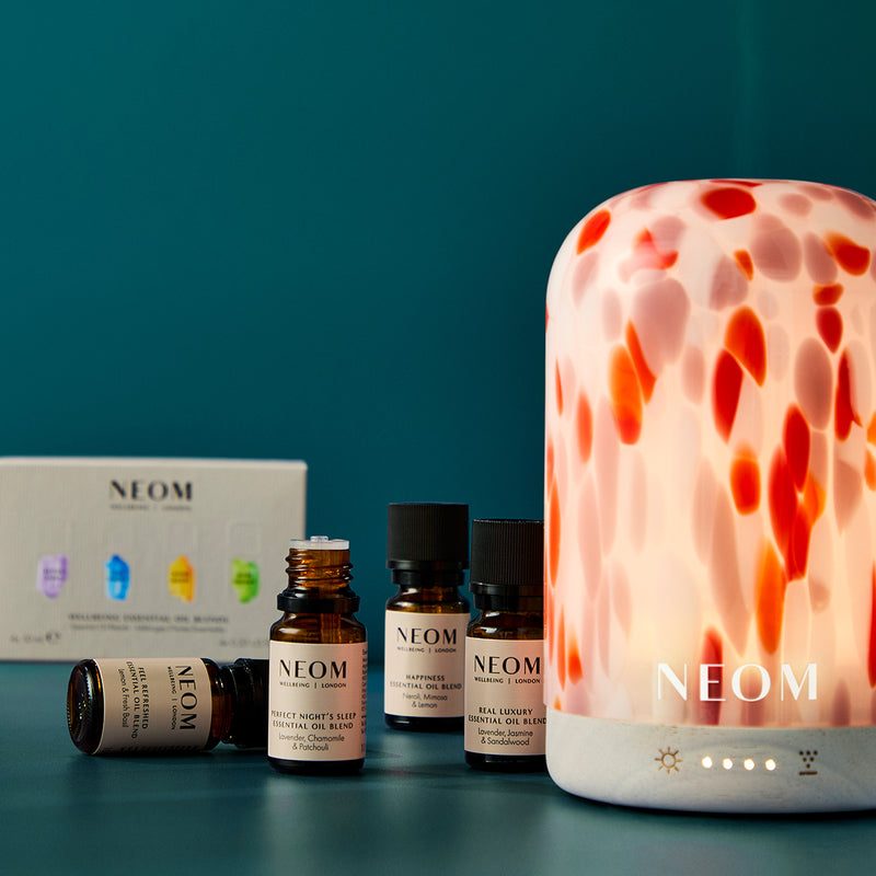 NEOM products including a diffuser, essential oils and packaging on a teal background