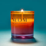 NEOM candle with a gradient colour on a blue background