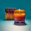 NEOM candle with packaging on a teal background