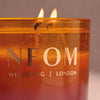 NEOM Cosy Night's 3 Wick Candle with flames on a neutral background