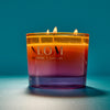 NEOM candle with a gradient color on a blue background