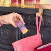 Person placing NEOM Cosy Nights Essential Oil Blend box into pink Christmas stocking on decorated mantel.