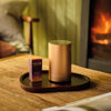 NEOM Rose Gold Pod Mini+ and Cosy Night's essential oil blend wooden table with a fireplace in the background