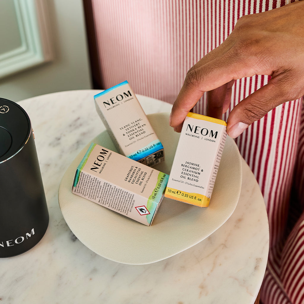 NEOM Essential Oil Blends on a table side with the Pod Mini+ in Black