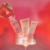 Hand holding NEOM skincare products against a red background