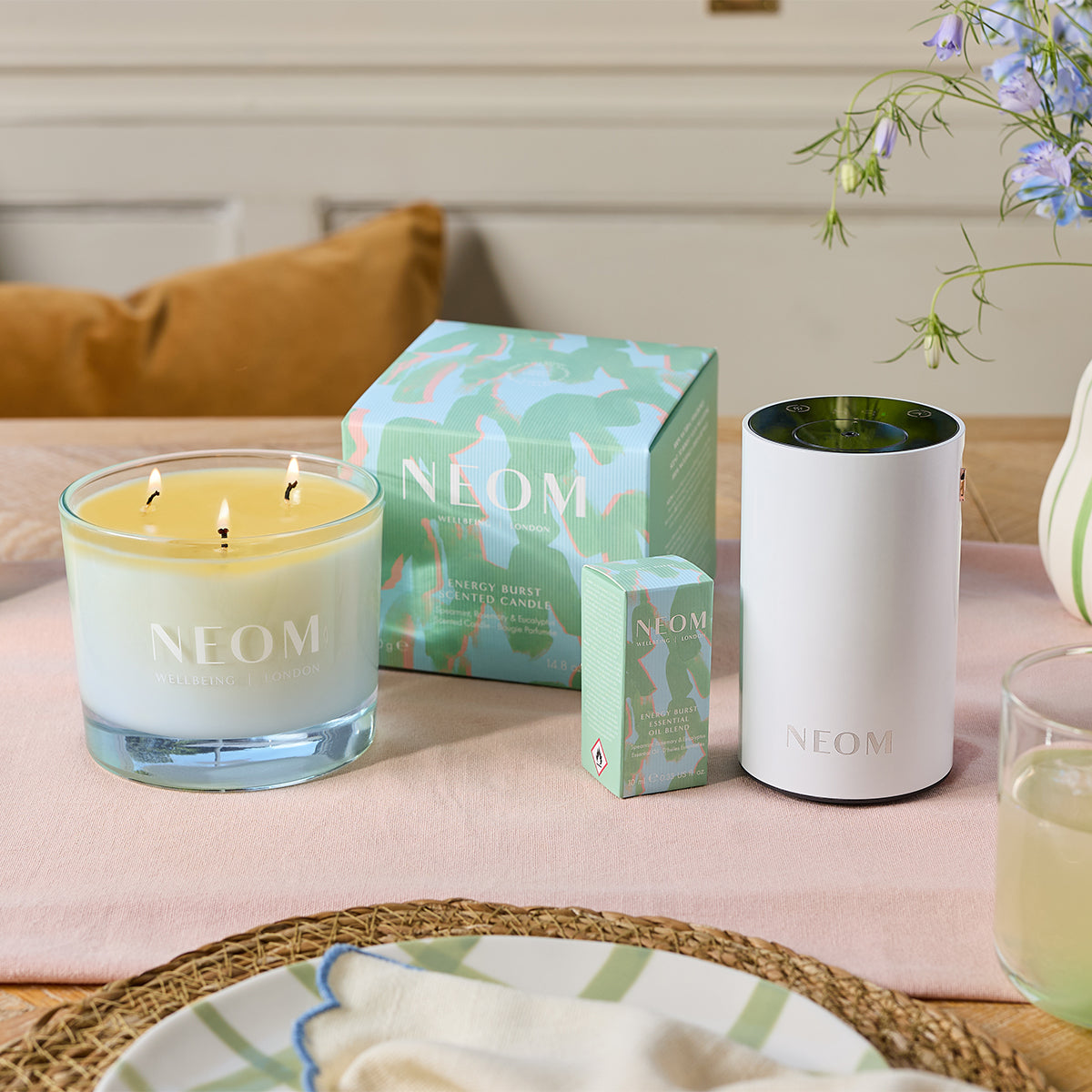 NEOM candles and packaging on a table with a soft pink surface