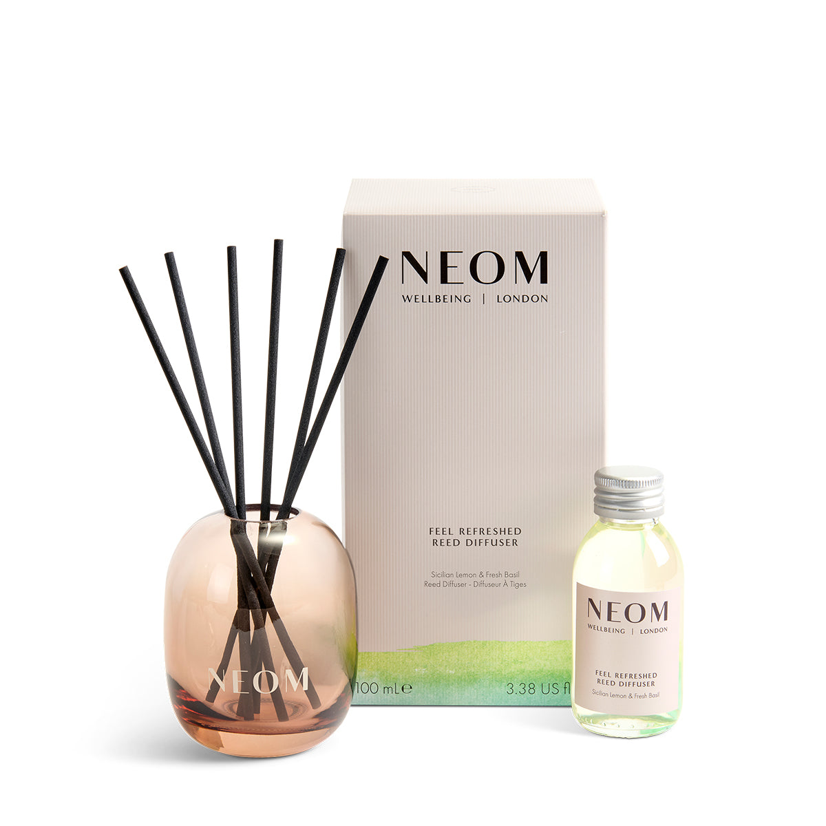 Neom diffuser set with rose gold diffuser, black reeds, and small bottle on a white background