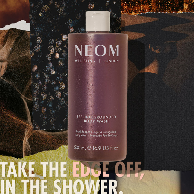 “NEOM Feeling Grounded Body Wash (500 ml) over a collage of dark, textured ingredients. Text reads: ‘Take the edge off, in the shower.’”