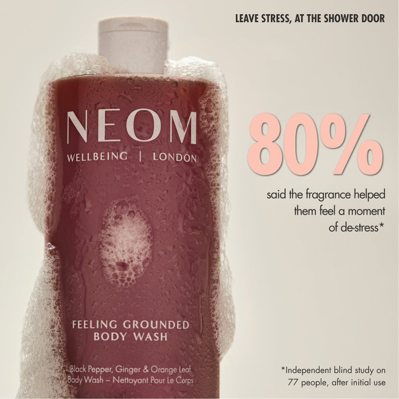 “NEOM Feeling Grounded Body Wash bottle covered in foam on a neutral background. Text reads: ‘Leave stress, at the shower door. 80% said the fragrance helped them feel a moment of de-stress*’. Small print: ‘*Independent blind study on 77 people, after initial use.’”