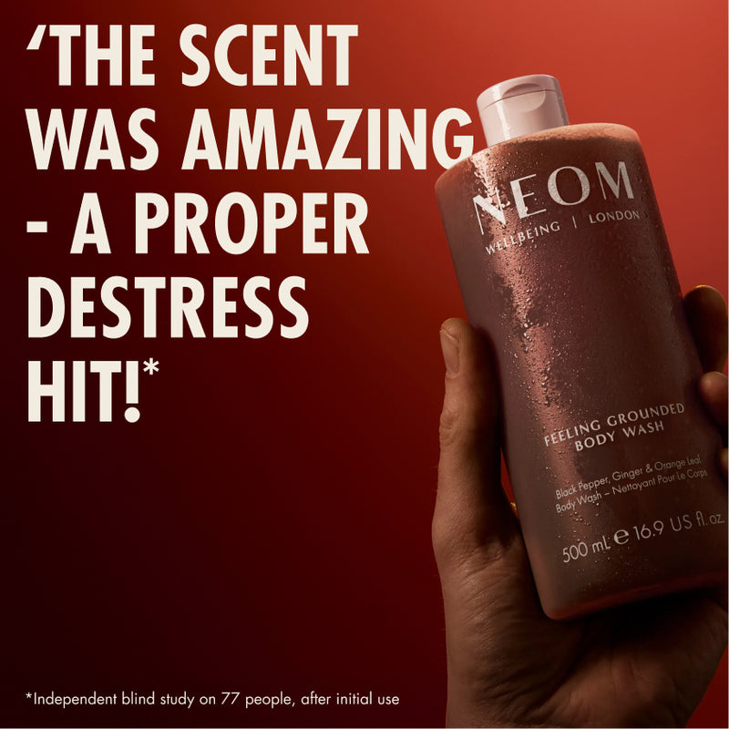 “Hand holding NEOM Feeling Grounded Body Wash against a red background. Large text reads: ‘The scent was amazing – a proper destress hit!’ Small print: ‘*Independent blind study on 77 people, after initial use.’”