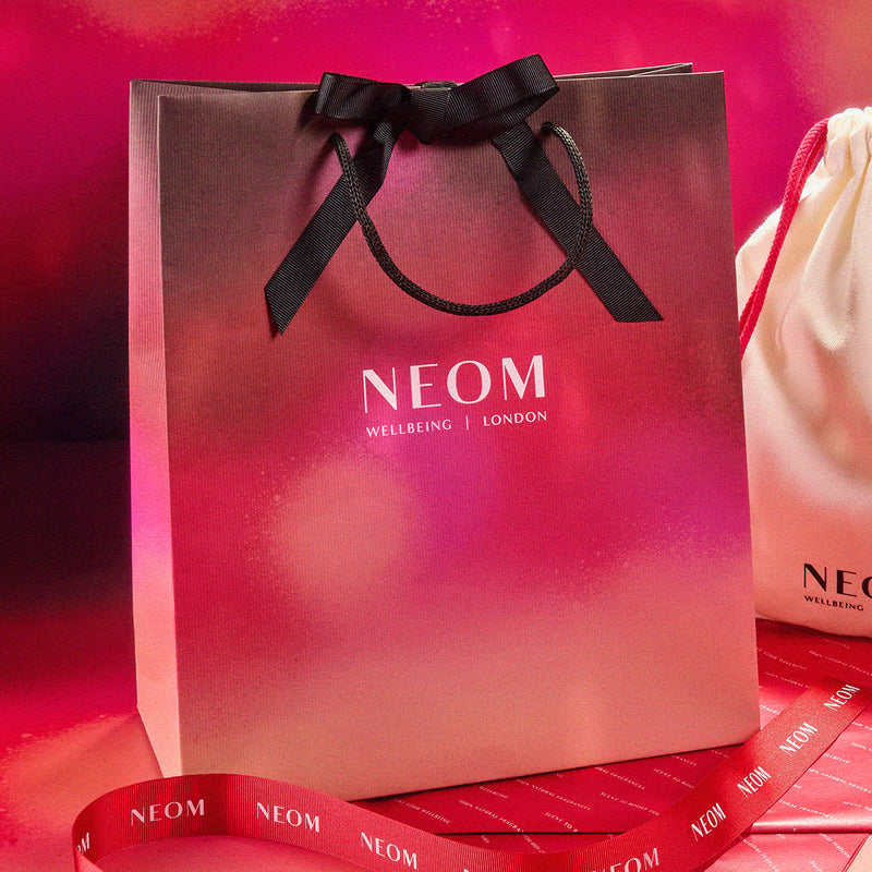 NEOM gift bag with a black ribbon on a red background