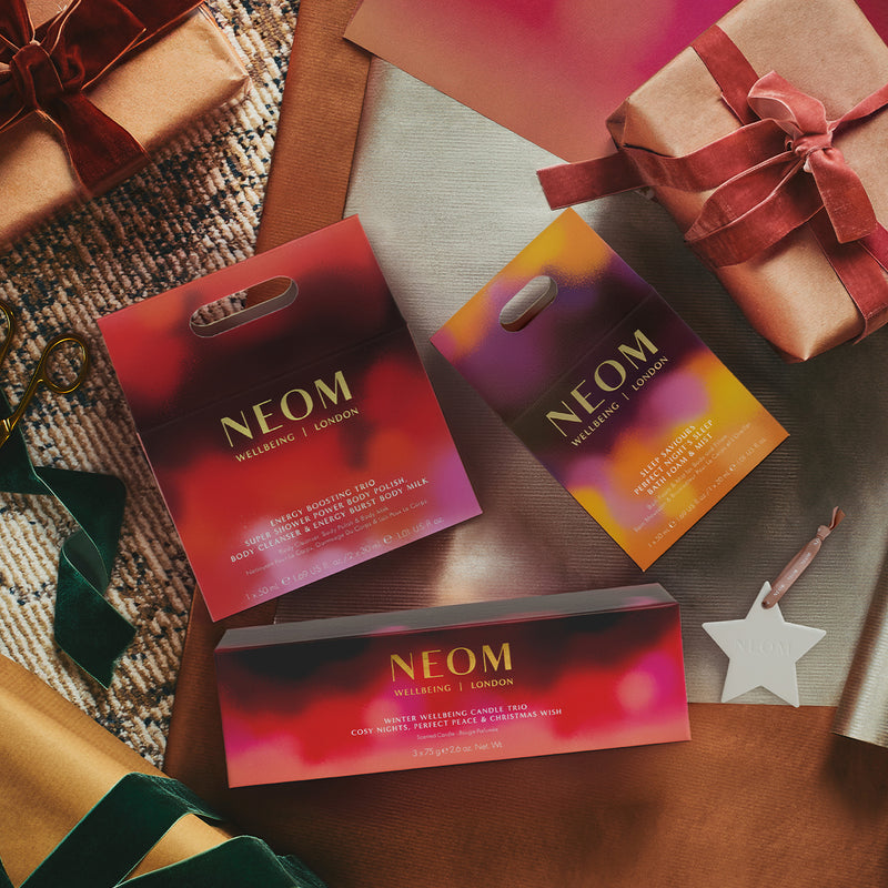 NEOM christmas gift sets on a festive background with wrapped gifts