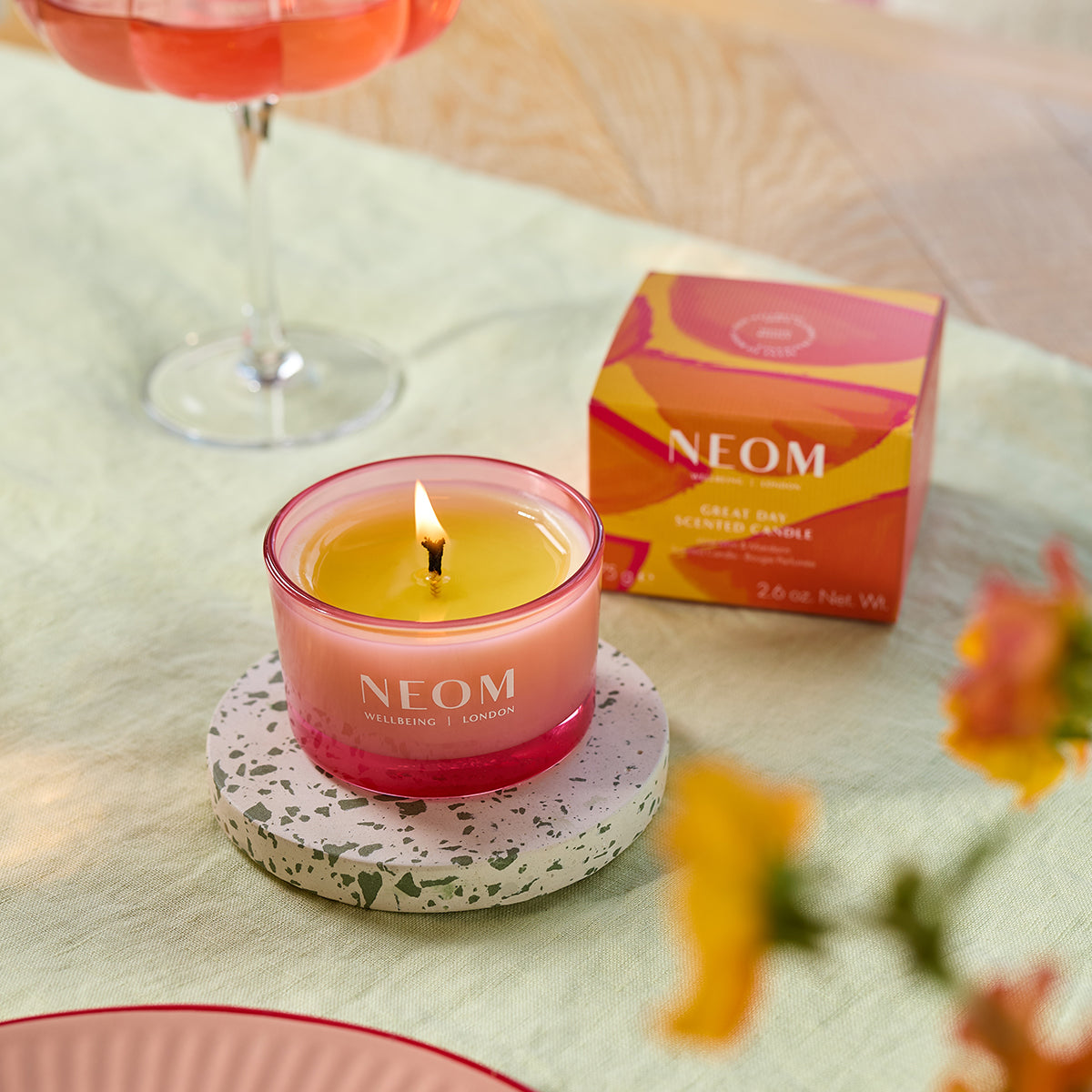 Neom candle on a table with a box in the background