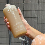 NEOM great day body wash in the shower being held by a person