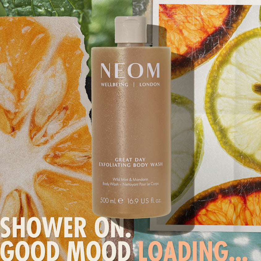 “NEOM Great Day Exfoliating Body Wash (500 ml) centered over a collage of citrus slices and greenery. Text reads: ‘Shower on. Good mood loading…’”