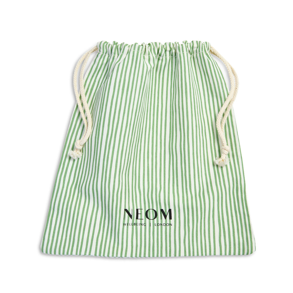 A green and white striped drawstring bamboo bag with the brand name 'NEOM' printed on the front.