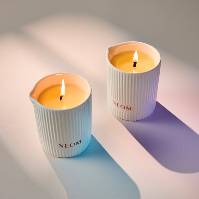 Two NEOM candles on a light background