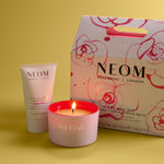 NEOM candle, hand balm, and packaging on a yellow background