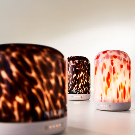 Three patterned NEOM pod diffusers on a light background