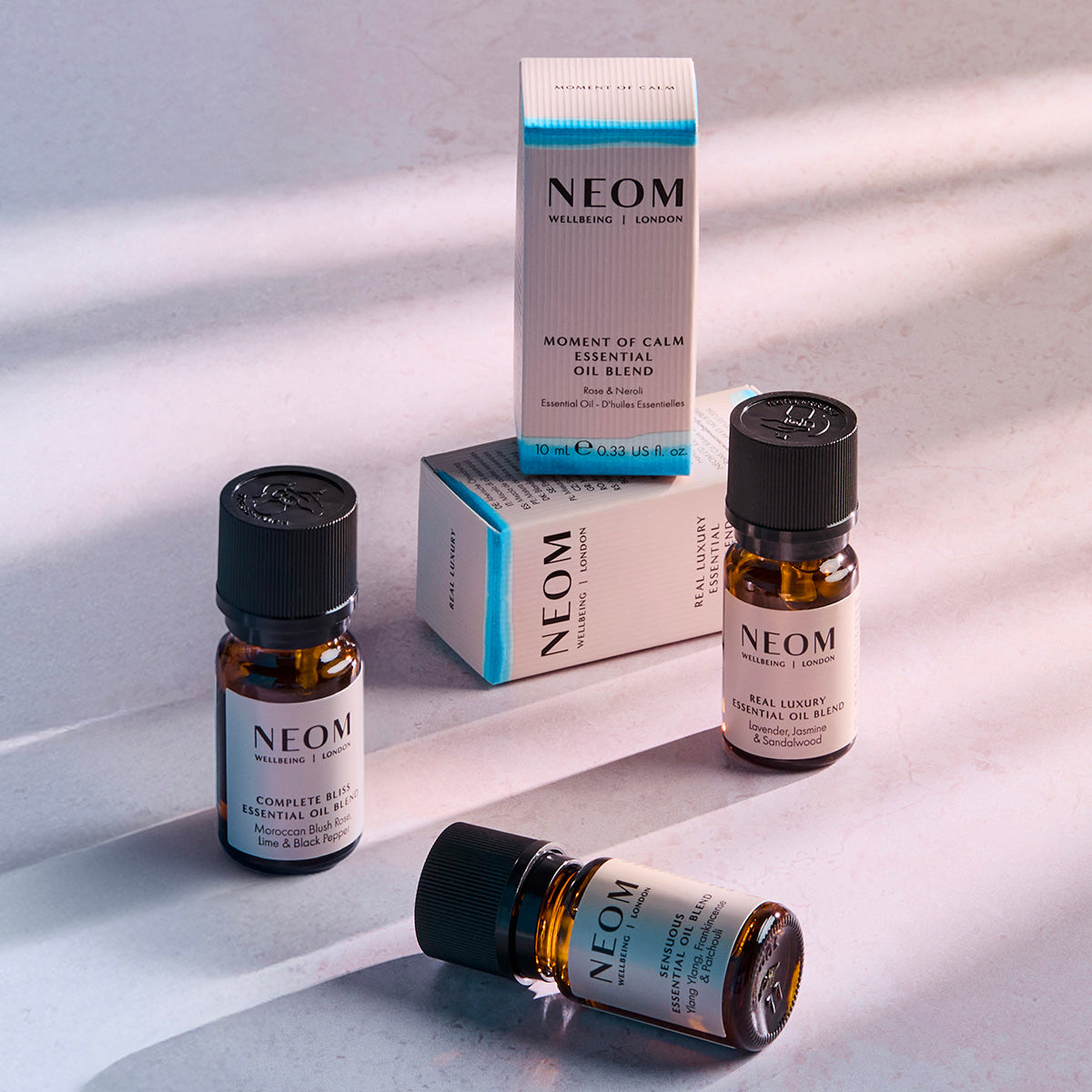 NEOM Less Stress core collection featuring essential oil blend bottles and boxes