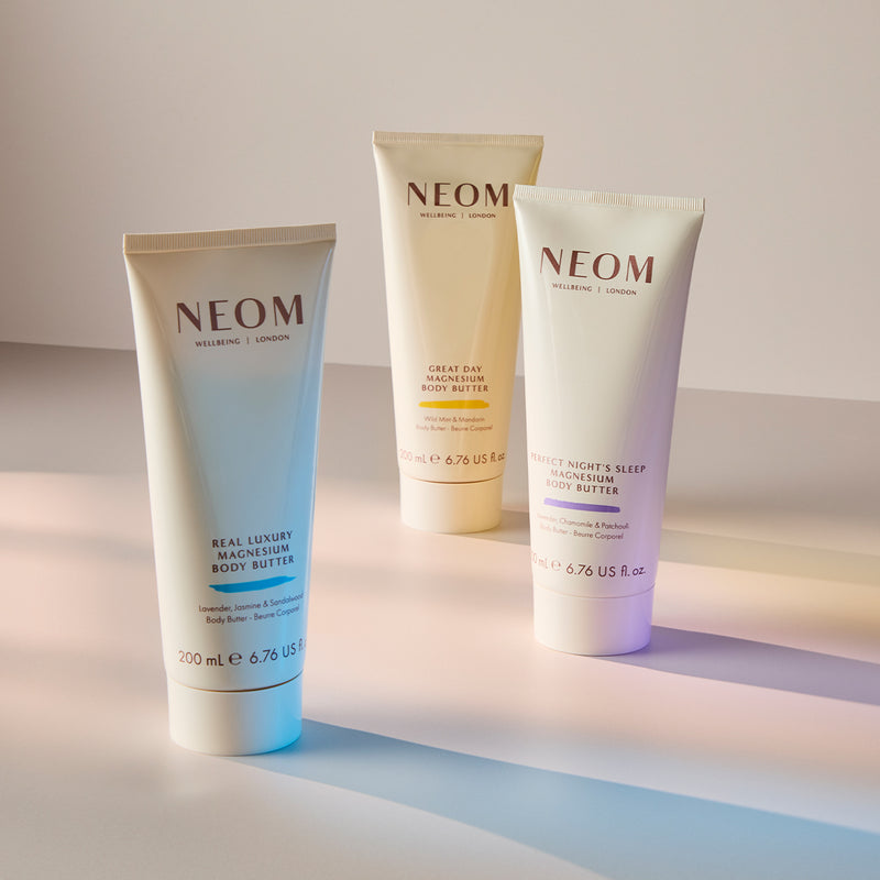Three NEOM magnesium body butters on a gradient background