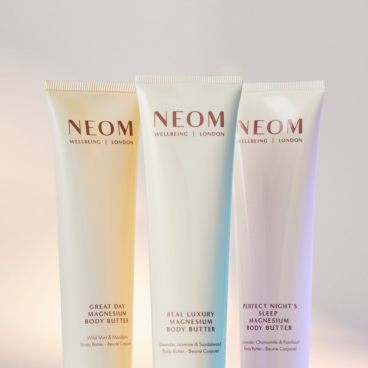Three NEOM magnesium body butters on a gradient background