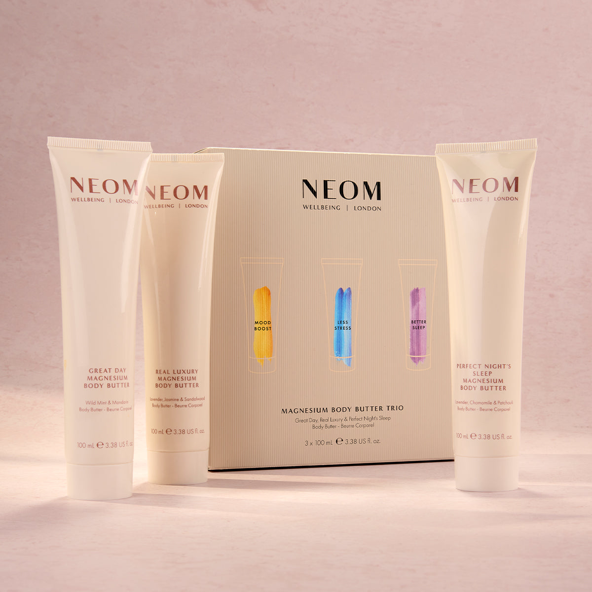 Three NEOM magnesium body butter products on a pink background