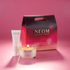 NEOM products including a candle, body milk, and packaging on a pink background