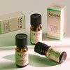 Three NEOM Wellbeing essential oil bottles and two boxes arranged on a light background, showing the Focus the Mind, Feel Refreshed, and Grapefruit, Mandarin & Eucalyptus blends.