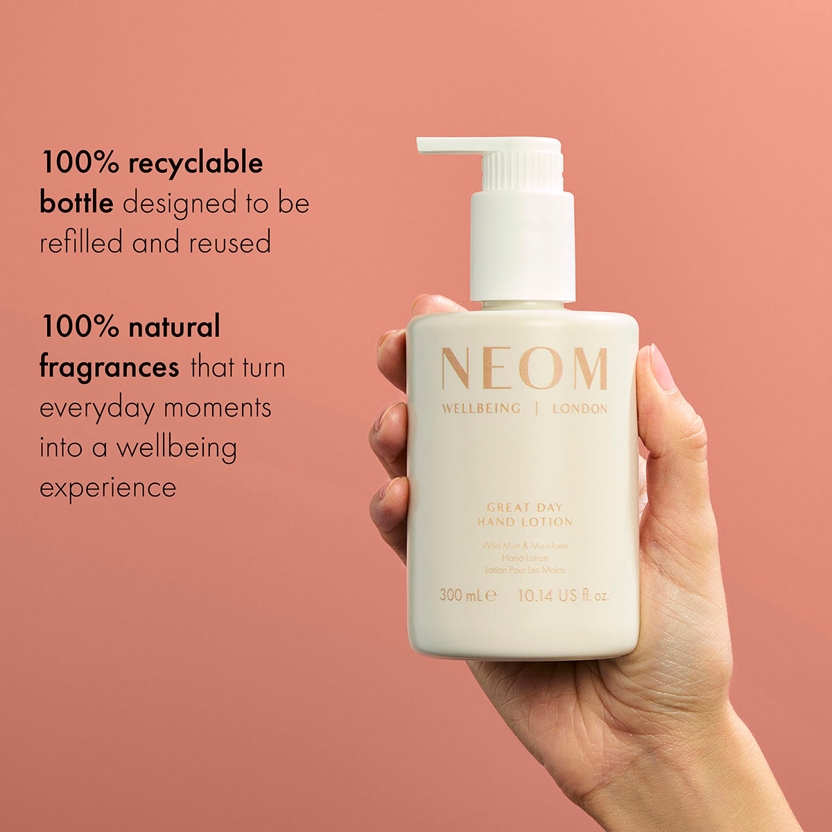 NEOM Great Day Hand Lotion bottle held in hand on coral background, 100% recyclable and natural fragrance skincare
